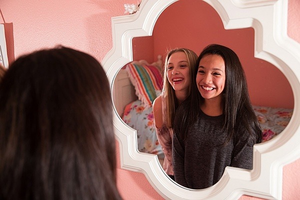 Zwei Mädchen schauen lächelnd in den Spiegel