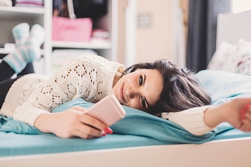 Jugendliche auf Bett mit Smartphone
