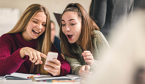 Zwei Jugendliche schauen zusammen auf Handy