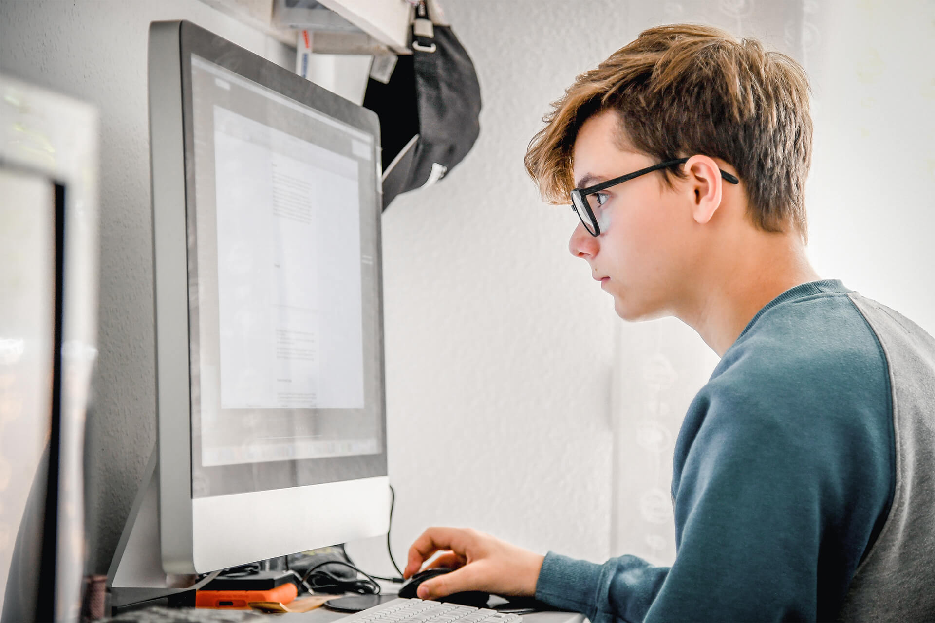 Teenager sitzt am Computer und surft im Internet.