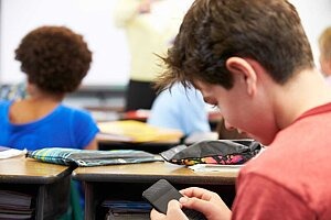 Lehrerin nimmt Mädchen ihr Smartphone im Unterricht weg.