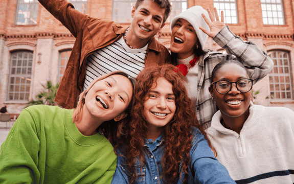 Fünf Jugendliche lachen und winken