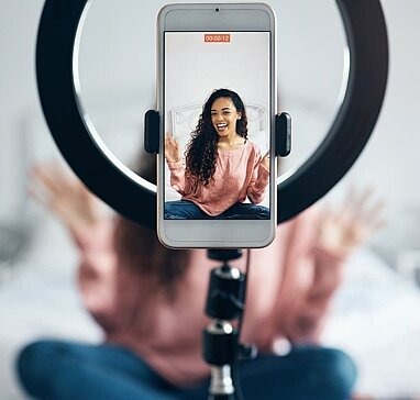 Junge Frau nimmt Video mit Smartphone und Ringlicht auf