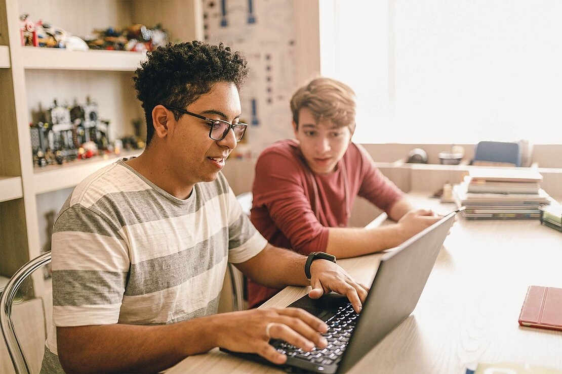 Zwei Jungen sitzen vor Laptop