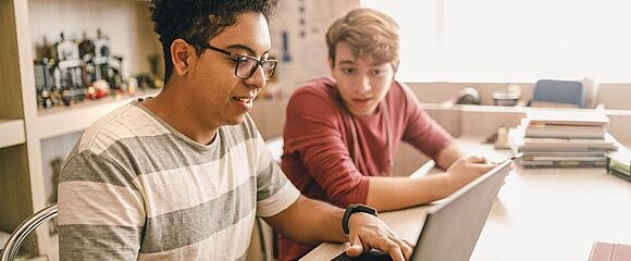 Zwei Jungen sitzen vor Laptop