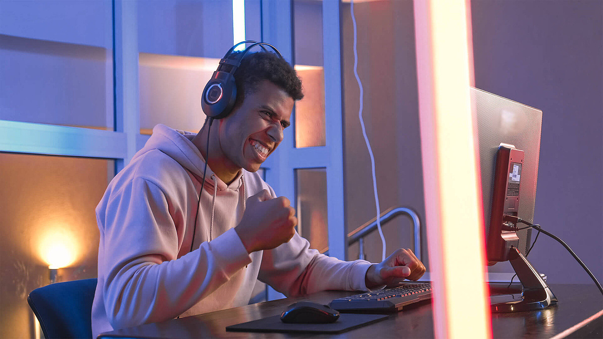 Junger Mann sitzt am Computer und gewinnt ein Online-Spiel.