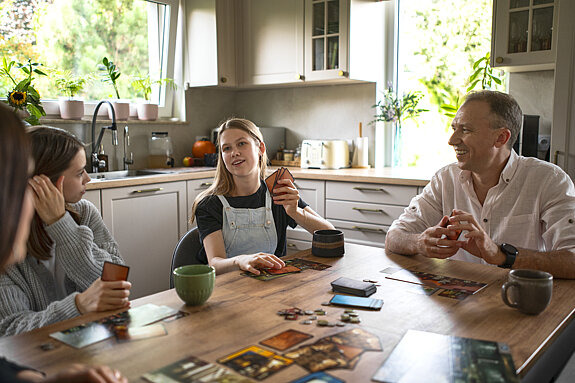 Familie spielt Kartenspiel am Küchentisch