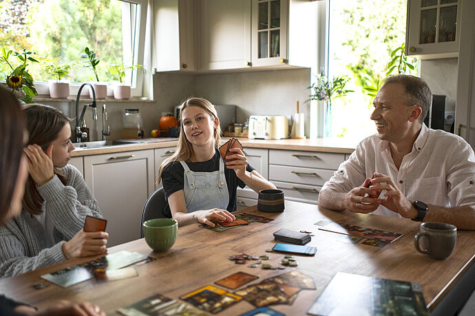Familie mit zwei jugendlichen Kindern spielt ein Kartenspiel.