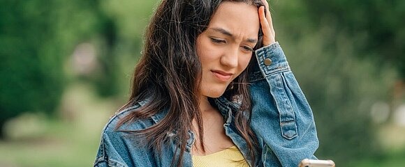 Jugendliche guckt besorgt auf ihr Smartphone