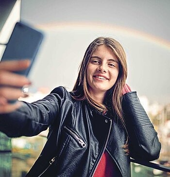 Mädchen macht Selfie vor Regenbogen