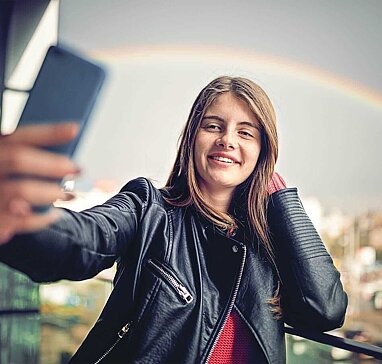 Mädchen macht Selfie vor Regenbogen