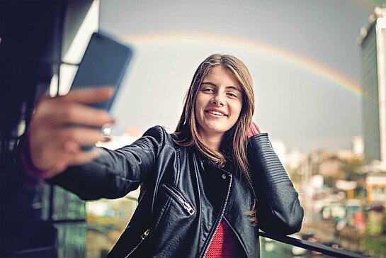 Mädchen macht Selfie vor Regenbogen