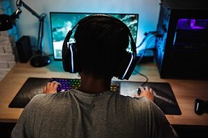Jugendlicher spielt im dunklen Zimmer Computerspiele
