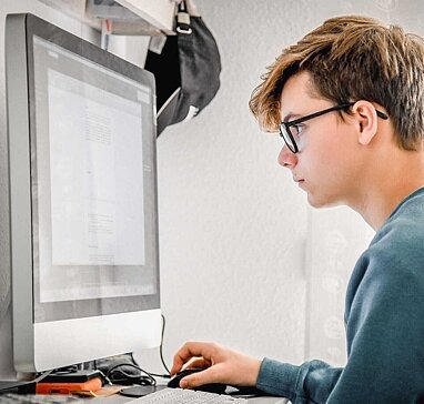 Jugendlicher guckt konzentriert auf den PC-Bildschirm.