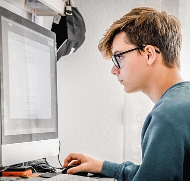 Jugendlicher guckt konzentriert auf den PC-Bildschirm.