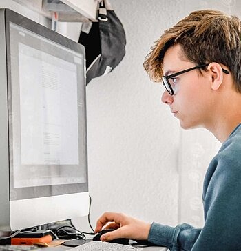 Jugendlicher guckt konzentriert auf den PC-Bildschirm.
