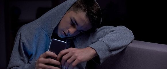 Junge schaut am Smartphone Pornos.