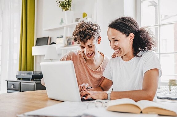 Mutter und Sohn zusammen lachend am Laptop