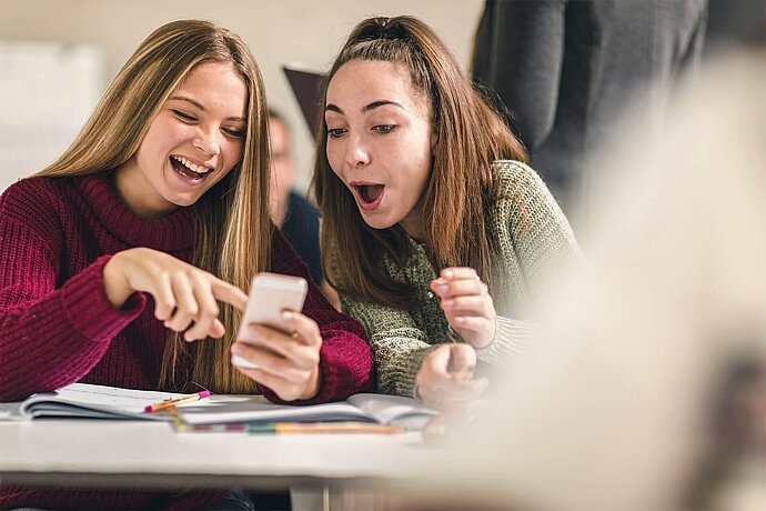 Zwei Jugendliche schauen zusammen auf Handy