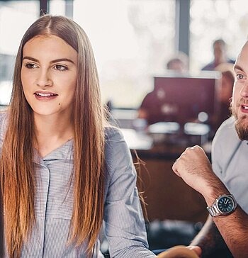 Berater sitzt mit junger Frau am Computer.