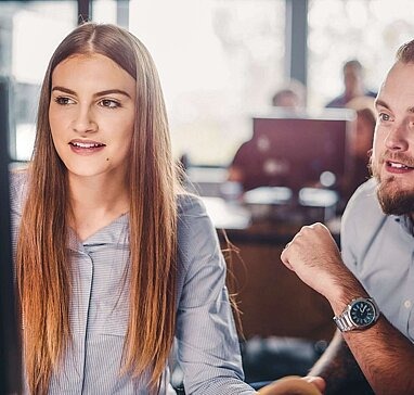 Berater sitzt mit junger Frau am Computer.