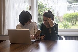 Mutter und Tochter sitzen vor dem Laptop