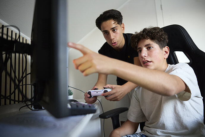 Zwei Teenager spielen am PC.