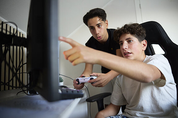 Zwei Teenager spielen am PC.