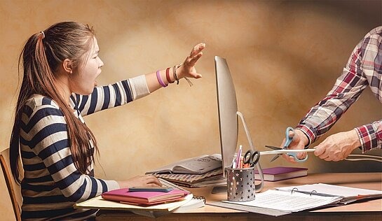 Vater schneidet das Computerkabel durch, während das Mädchen vor dem Computer protestiert.