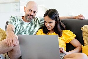 Vater zeigt seinem Sohn etwas auf dem Laptop.