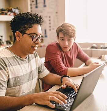 Zwei Teenager arbeiten an einem Laptop.