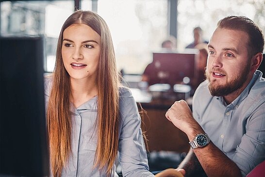 Mann berät eine Jugendliche am PC.