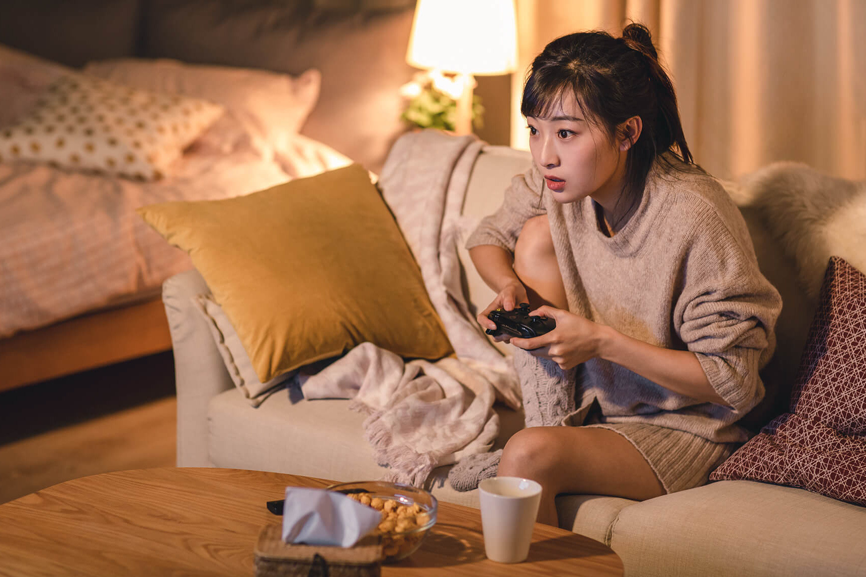 Jugendliche sitzt auf Sofa mit Controller in der Hand