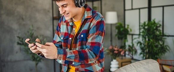 Jugendlicher spielt Handygame mit Kopfhörern