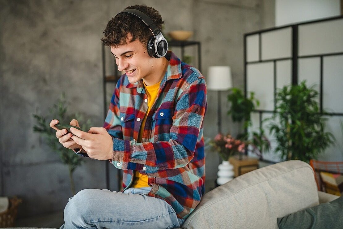 Jugendlicher spielt Handygame mit Kopfhörern
