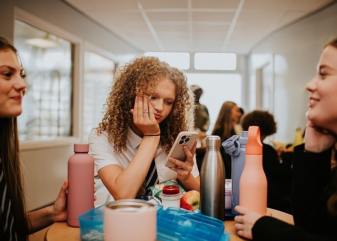 Jugendliche schaut traurig auf Handy während Schulpause