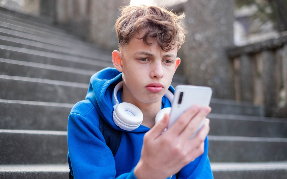 Junge schaut traurig auf Smartphone