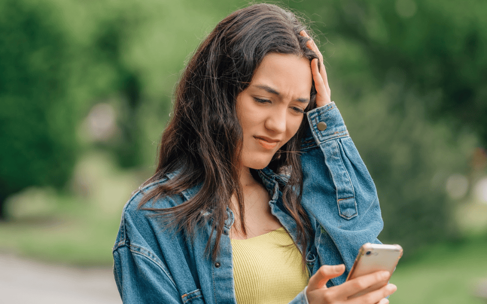 Mädchen schaut besorgt auf Smartphone