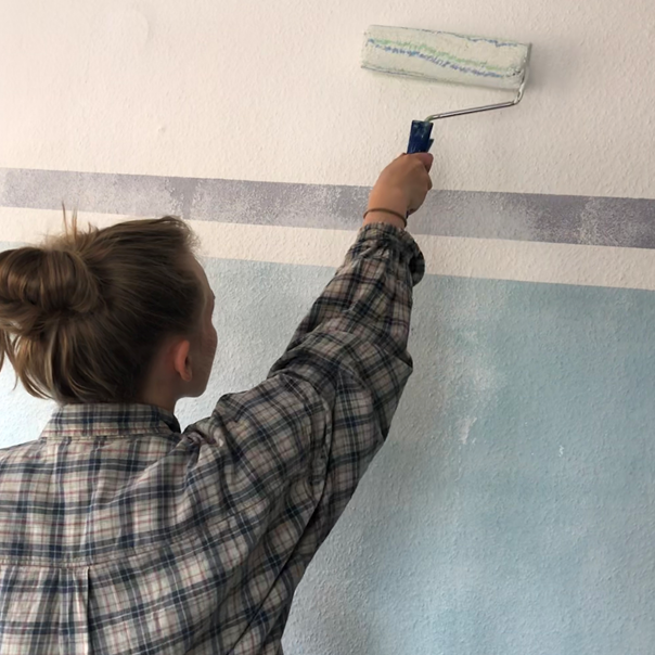 Junge Frau streicht eine Wand 